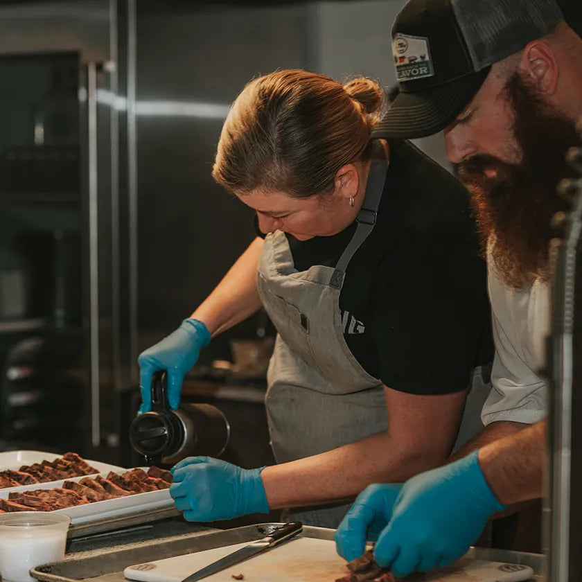 Professional chefs carefully preparing Joyce Farms heritage meat in a restaurant kitchen, showcasing the dedication to quality and flavor.