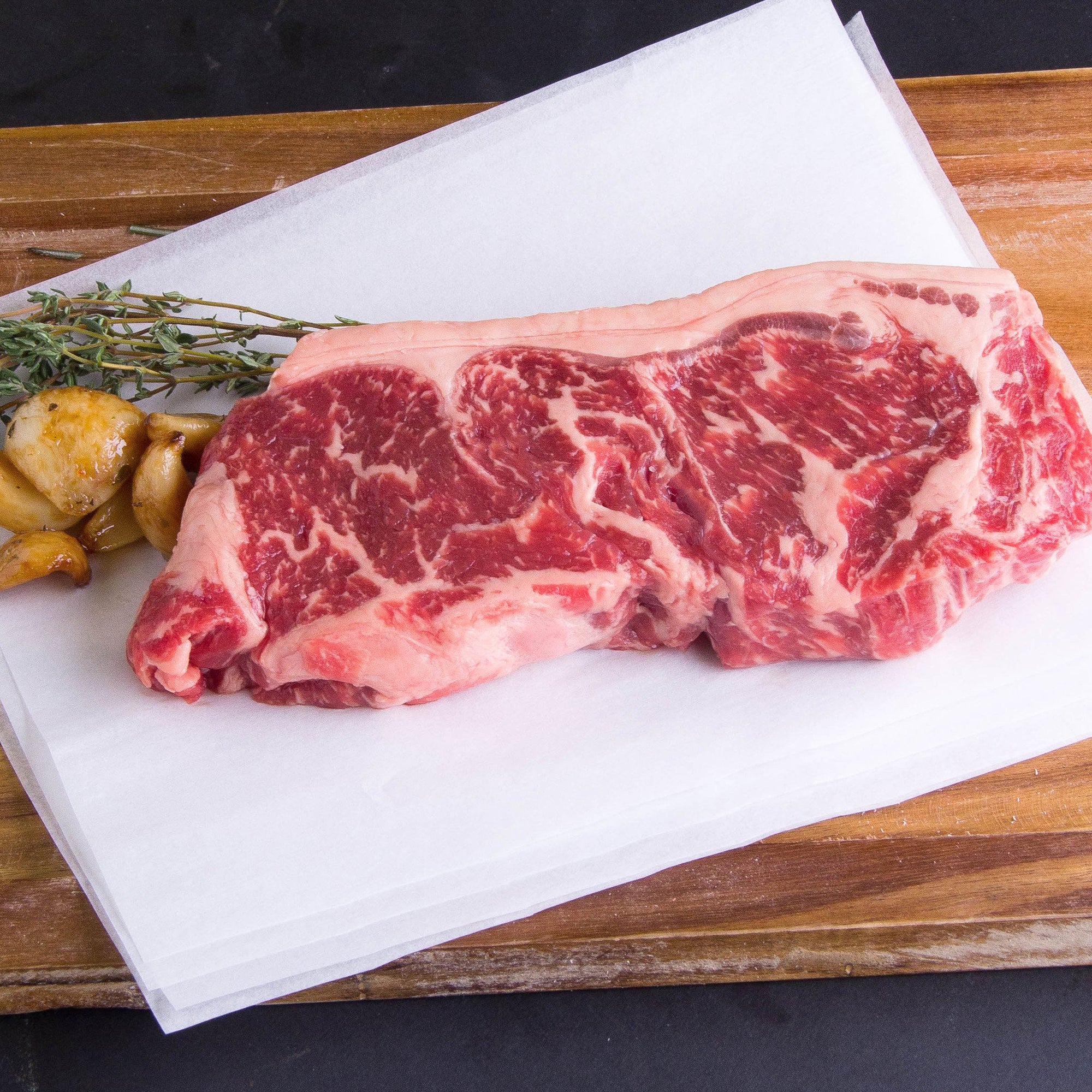 A piece of Joyce Farms Heritage Grass-Fed Beef New York strip steak on a cutting board.