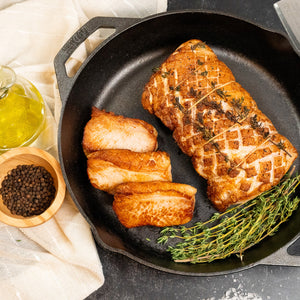 Cooked pork sirloin end loin seared in a cast iron skillet with sliced portions, fresh thyme, black pepper, and olive oil.