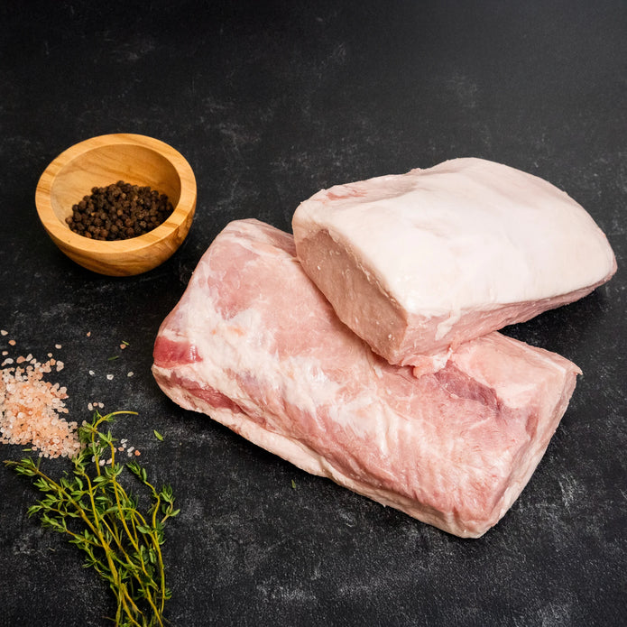 Raw pork sirloin end loin portions on a dark surface with sea salt, black pepper, and fresh thyme.