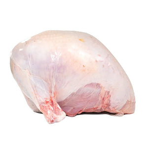Side view of a raw Heritage Black Turkey Bone-In Breast, isolated on a white background.