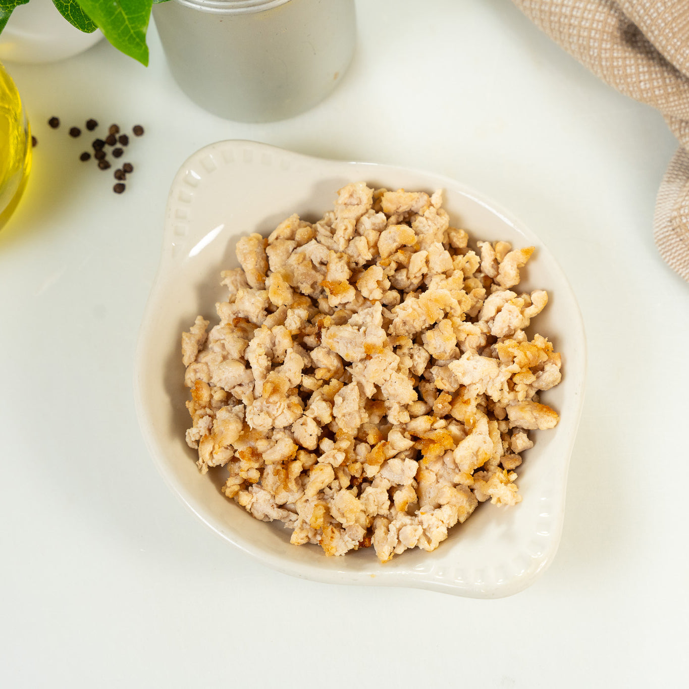 Bowl of ground meat on a white surface with a light background