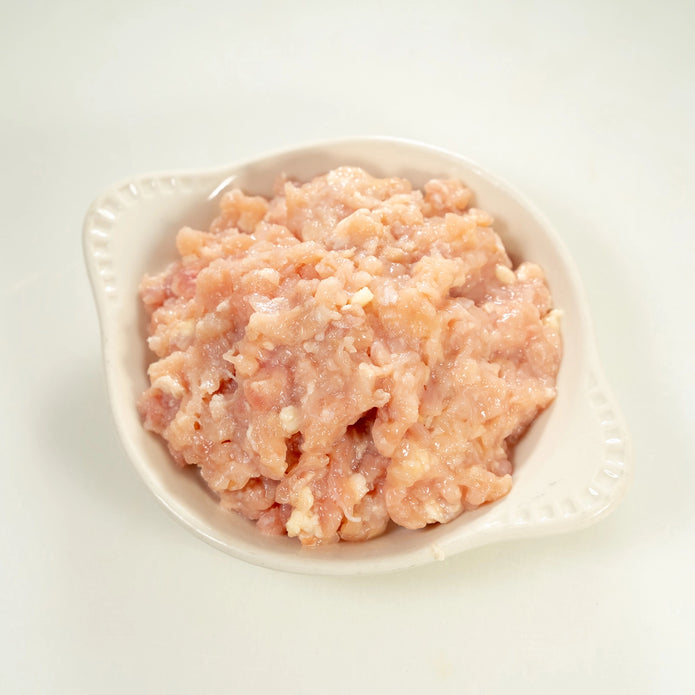 raw joyce farms naked ground chicken in a white bowl with a light background