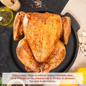 A whole roasted turkey on a black serving platter, seasoned with salt and pepper, surrounded by lemons, garlic cloves, fresh herbs, and a bottle of oil on a dark tabletop. Text overlay reads: “Delivery Note: Ships as ordered, within 3 business days. Local Pickups can be scheduled up to 30 days in advance. See note in description.