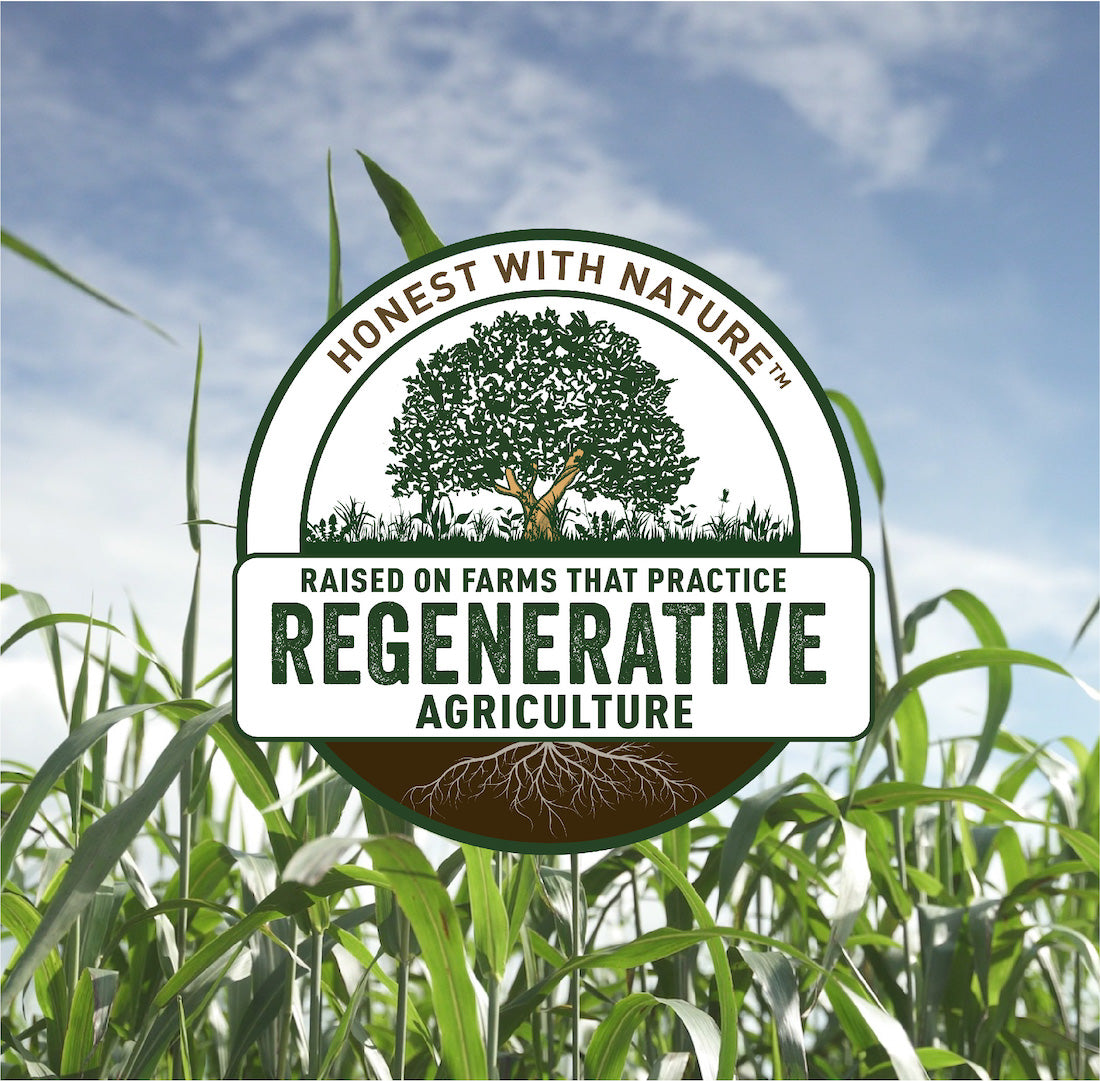 A lush green pasture at Joyce Farms, featuring the Joyce Farms Honest with Nature™ Regenerative Agriculture program icon prominently displayed against a blue sky.