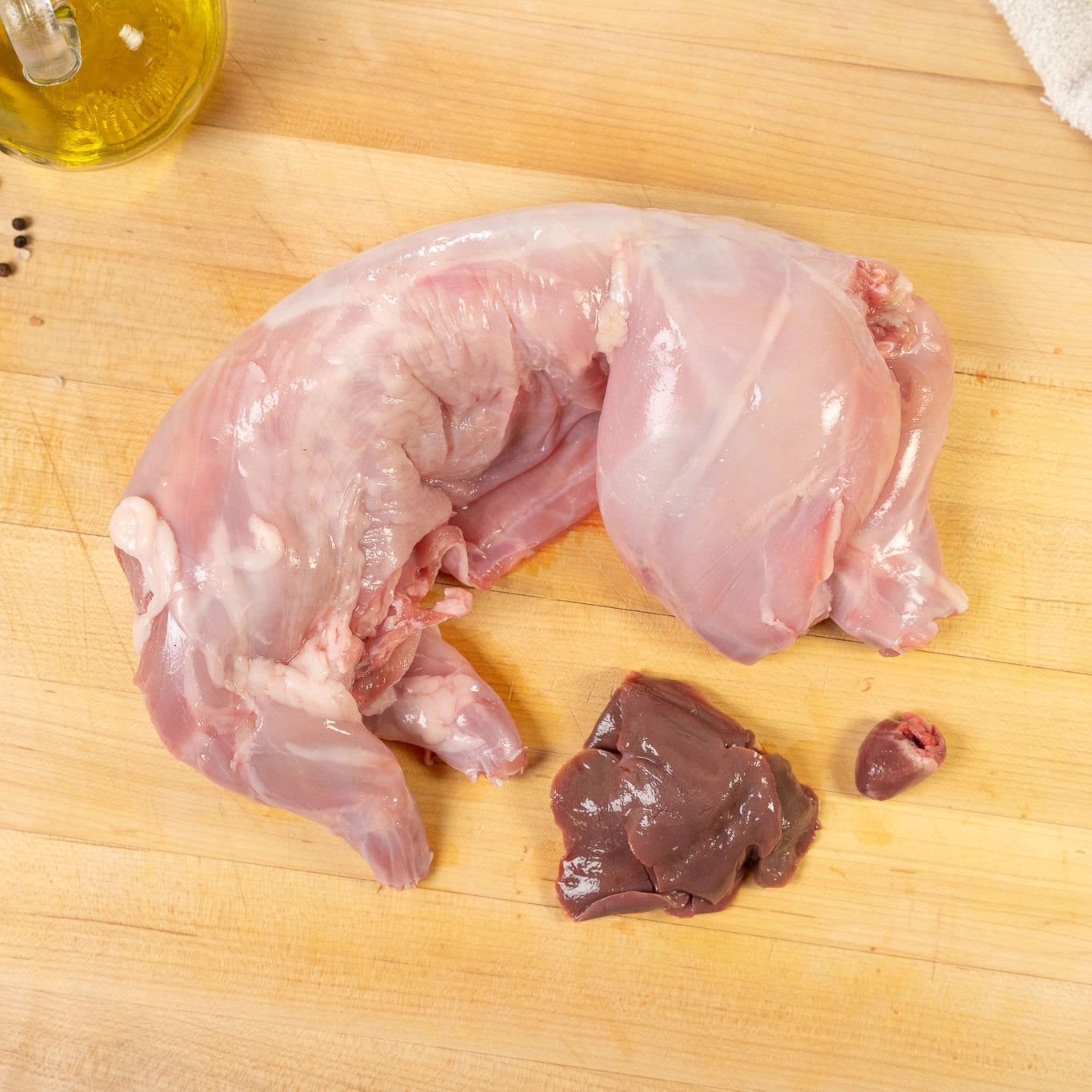Raw Naked Rabbit on wooden cutting board with the liver and heart resting next to the whole rabbit protein