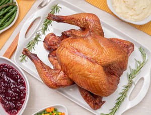 Joyce Farms Heritage Black Turkey cooked on thanksgiving table with cranberry sauce, mashed potatoes and green beans.