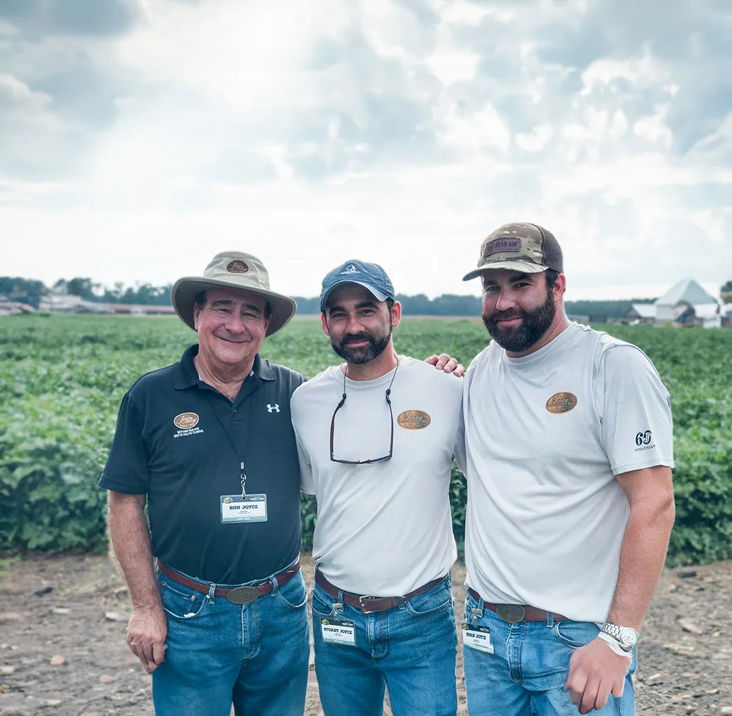 Joyce Farms family owners standing together in a field, showcasing their commitment to responsible farming and the highest quality all-natural and heritage breed meat, poultry, and game.